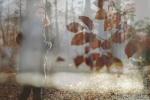 Doppelbelichtung Frau auf Waldweg mit Buchenblättern im Vordergrund