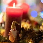 Adventsgesteck mit brennender Kerze und Wichtel