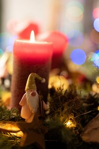 Adventsgesteck mit brennender Kerze und Wichtel