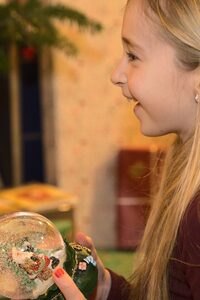 Ein Kind freut sich über eine Schneekugel, die es zu Weihnachten geschenkt bekommen hat