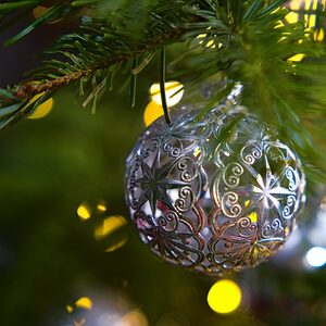 Eine Weihnachtskugel aus Silberblech die an einem Zweig hängt.